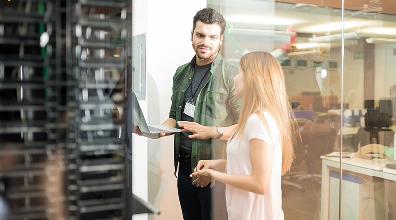 Two office workers talking in front of a server room