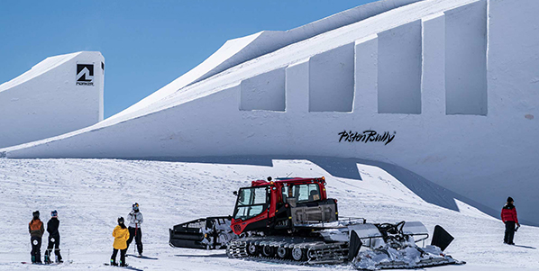 A Kässbohrer PistenBully and snowboarders against the background of the Nines