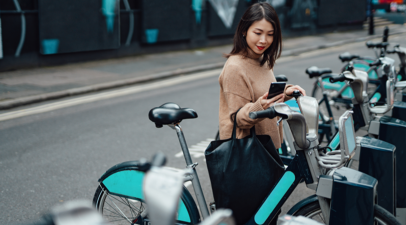 Frau mit Mobiltelefon benutzt vernetztes Fahrrad
