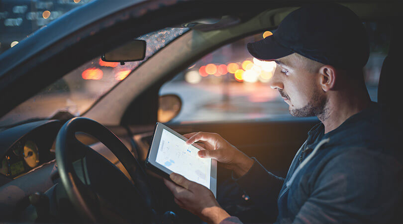 Mann im Auto prüft Echtzeit-Informationen zu seinen Aufträgen