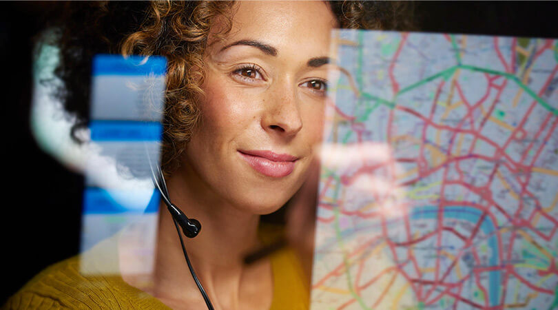 Woman with headset looks at screen with open road map