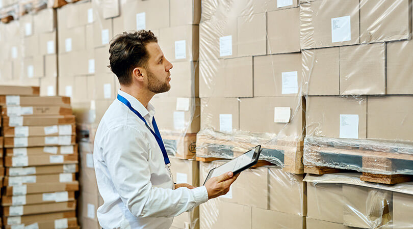 Man in front of stack of cartons checks quality of delivered goods