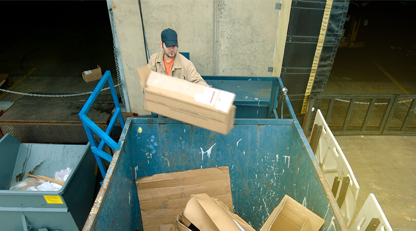 Mann entsorgt seine Verpackungsmaterialien und Abfälle in einem Container