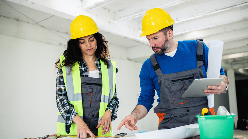 Woman and man with tablet studying building plans in the shell