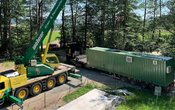 Kran hebt Wasseraufbereitungs-Container von Lkw