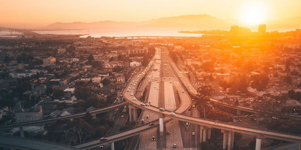 Bild mit Straßennetz in einer Großstadt und Sonnenuntergang sowie See als Hintergrund.