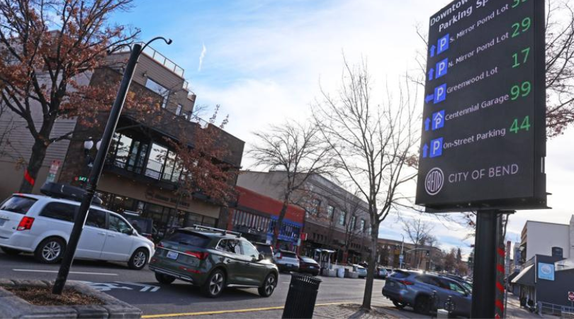 Straße mit Autos und elektronisches Parkhausschild.