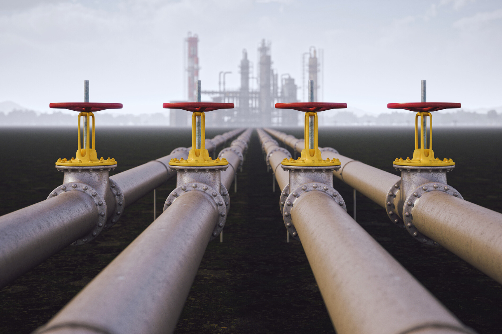 Industrielle Pipelines mit Ventilen, die eine Energieanlage im Hintergrund verbinden.