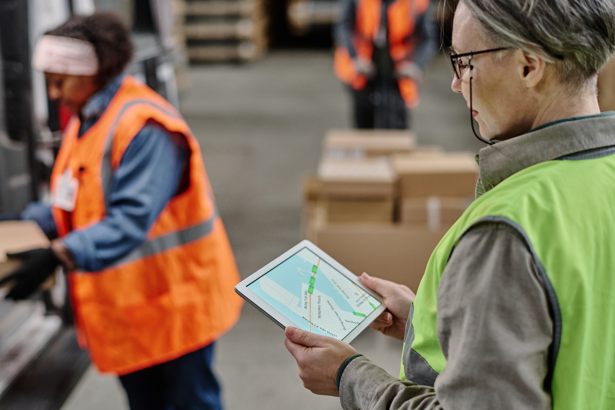 A warehouse worker is holding a tablet with a map on it.