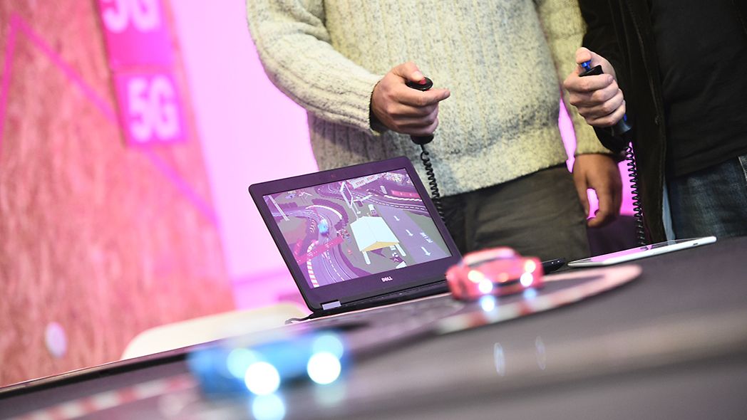 Zwei Personen demonstrieren die Funktionsweise von Connected Mobility auf einem Tablet.