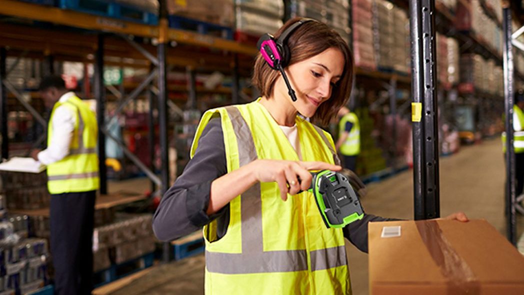 Lagermitarbeiterin scannt Paket mit Barcode-Scanner von Zebra