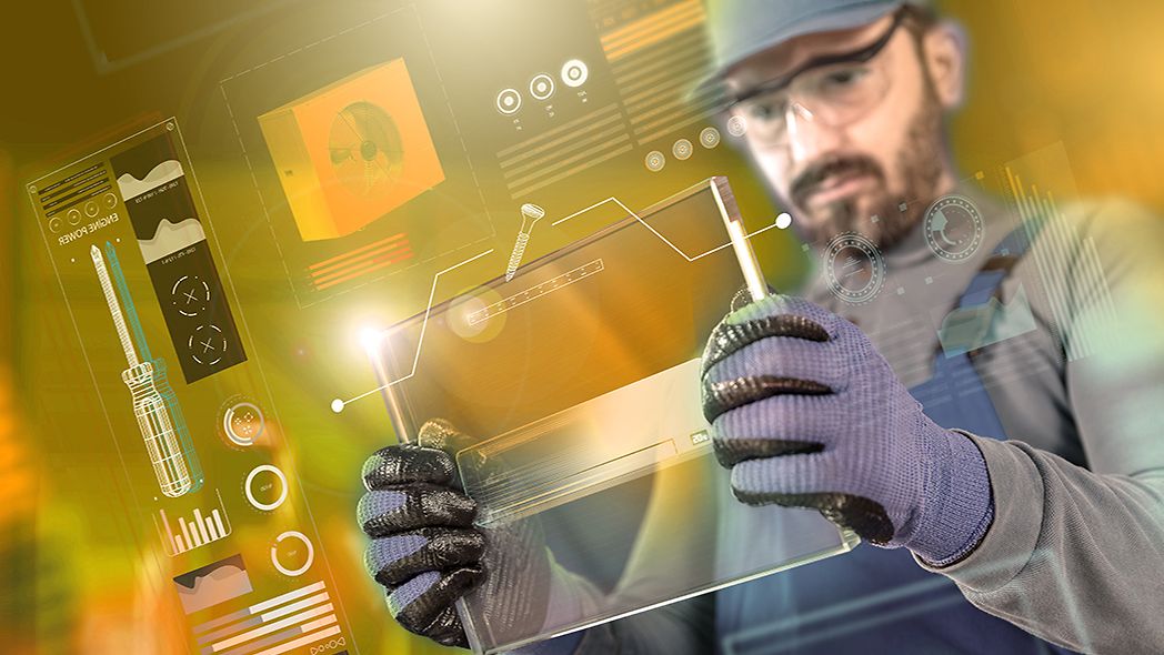 Mann mit Tablet in der Hand steht in einer Produktionshalle.
