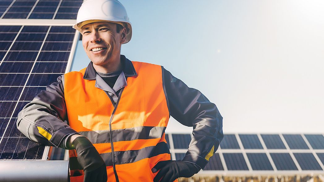Mann lehnt an Photovoltaikanlage auf einem Feld