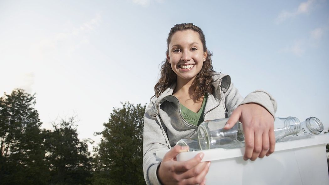 Frau bringt leere Flaschen zum Glascontainer
