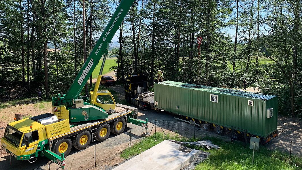 Kran hebt Wasseraufbereitungs-Container von Lkw