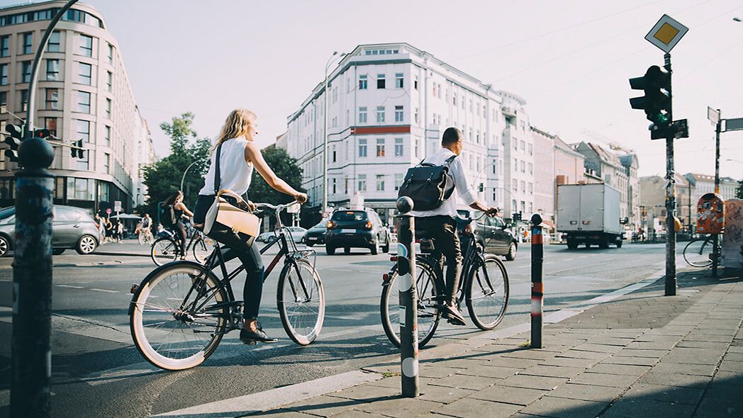 Mann fährt mit Fahrrad auf einer Straße, im Hintergrund eine Straßenbahn.