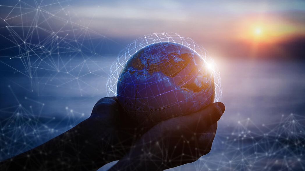 Two hands hold a globe and grid lines symbolize total connection.