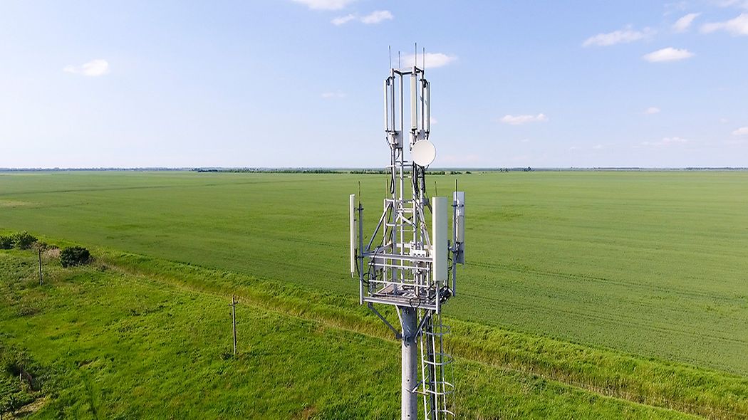 Radio mast with mobile phone antennas on a field