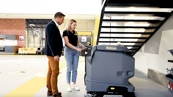 Two people operate a Kärcher scrubber dryer