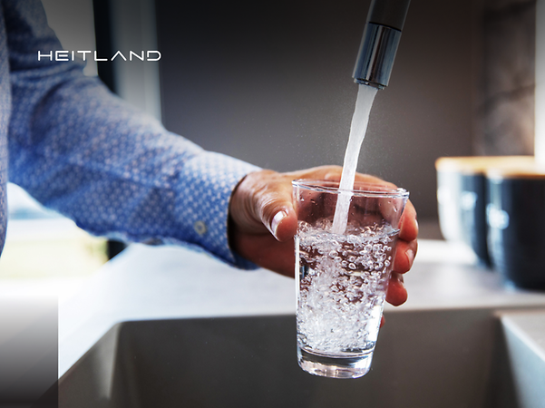 Logo von Heitland vor einer Person, die ein Wasseglas mit Wasser aus einem Wasserhahn auffüllt