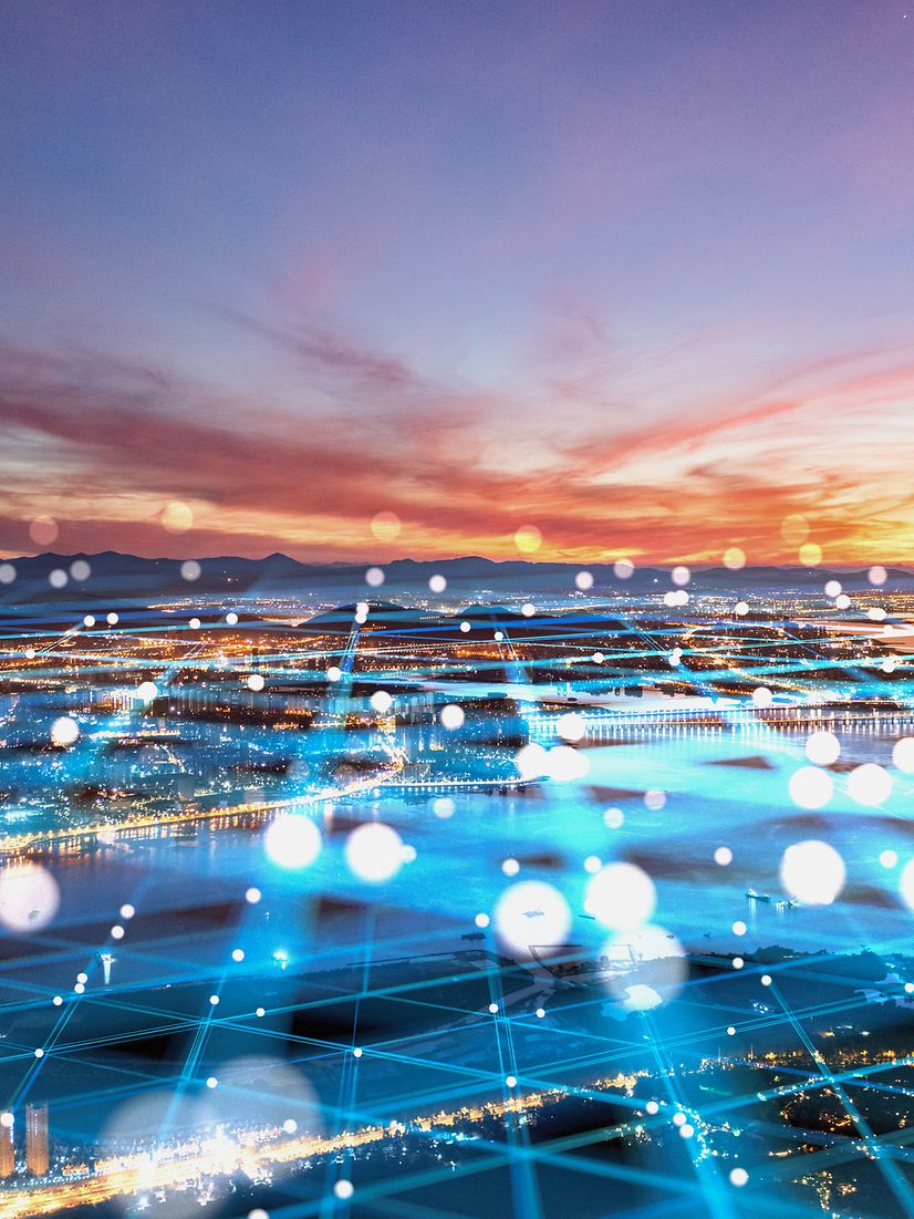 Stage backdrop for IoT use cases with a city and sunset background and an abstract network overlay.