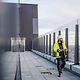 Man wearing a hard hat and holding a building plan on a building terrace