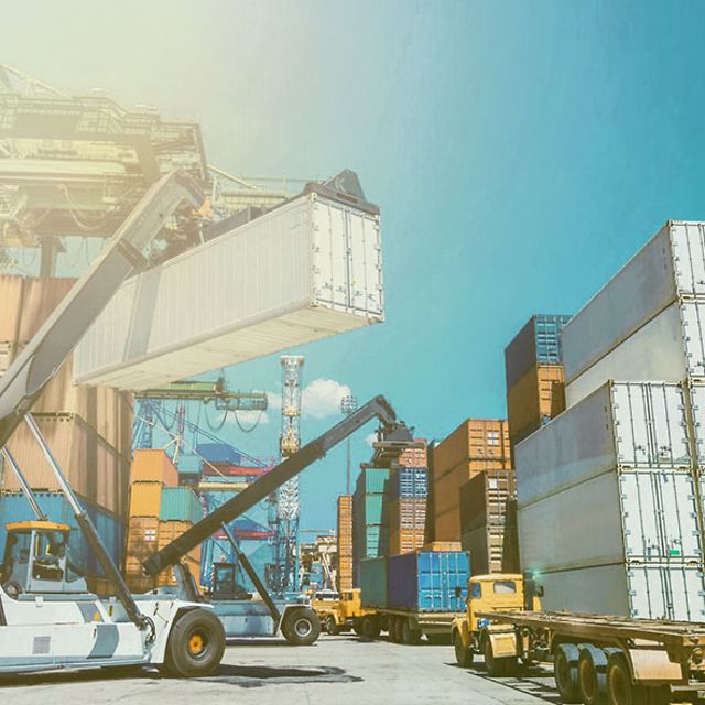 A crane stacks an IoT-connected container at a container depot.
