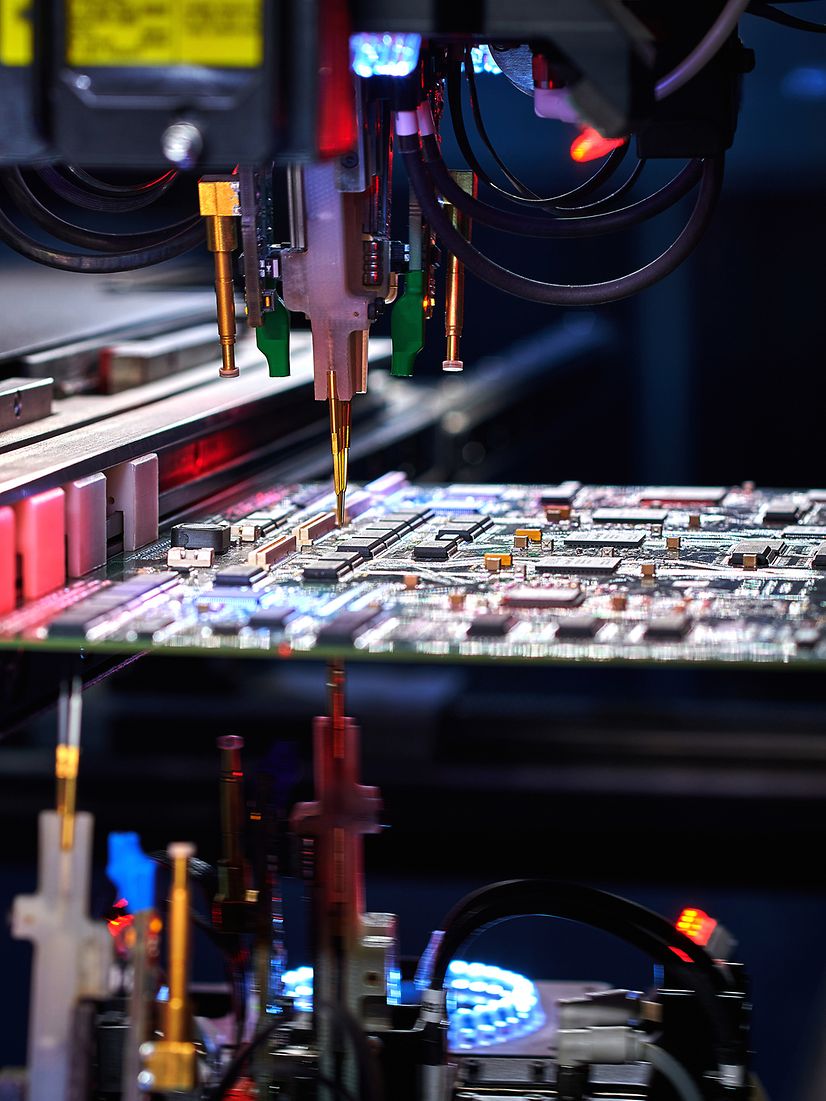 Robotic arm with IoT hardware assembles electronic components in a modern manufacturing environment.