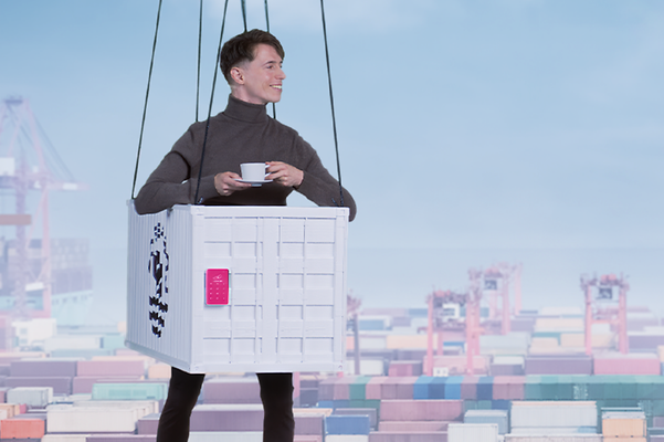 A person is wearing a container costume and hanging in front of a background depicting a container port.