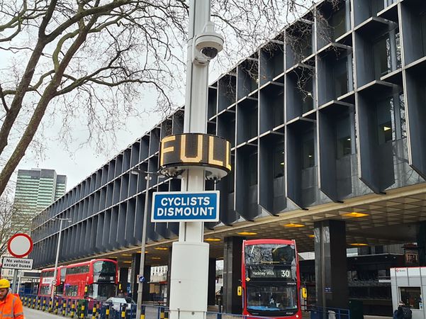 Grafik von einer Straße mit parkenden und fahrenden Autos, Straßenlaternen, einem Pakhaus und abstrakten bunten Linien.