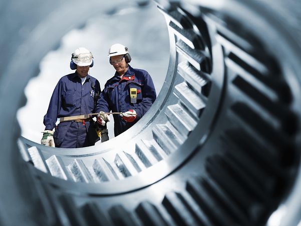 Two engineers photographed through a gear shaft.