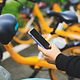 Person unlocking a rental bike using a smartphone app.