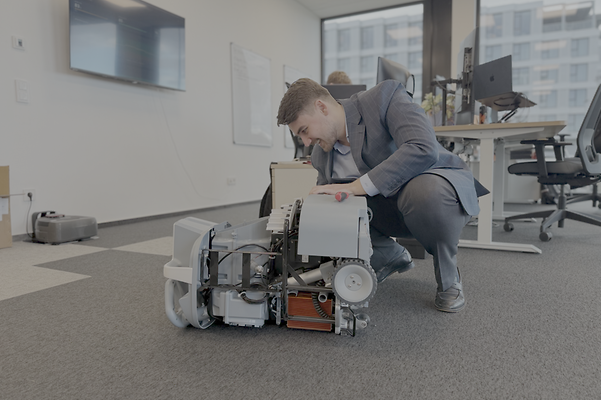 Nick Nidens repairs an autonomous cleaning robot in an office room.