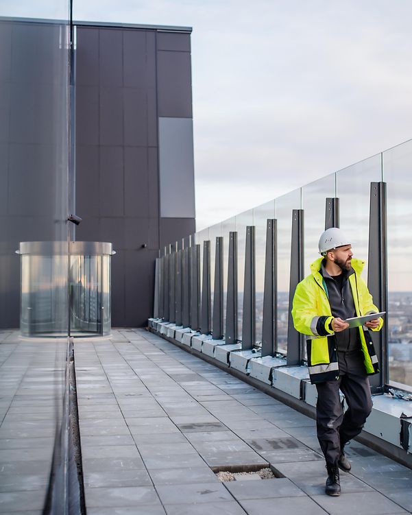 Man wearing a hard hat and holding a building plan on a building terrace