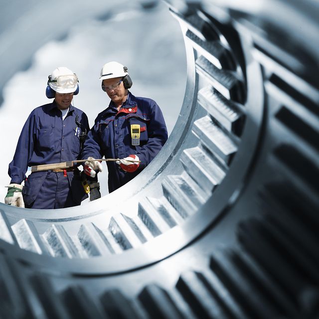Two engineers photographed through a gear shaft.