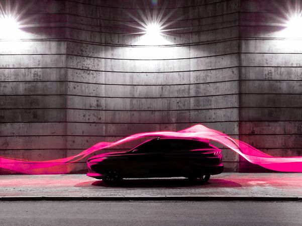 Un coche moderno iluminado por estelas de luz magenta que simbolizan la conectividad digital.