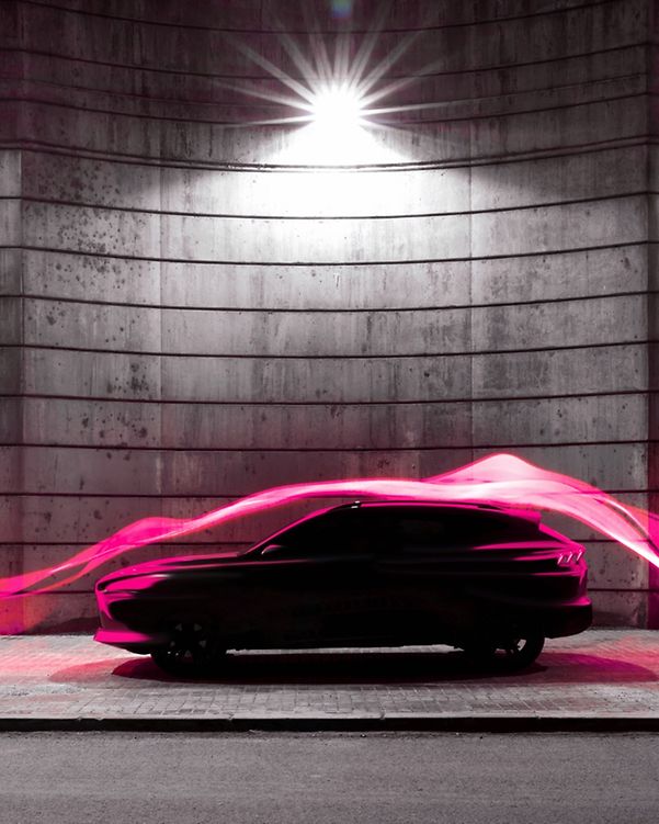 Un coche moderno iluminado por estelas de luz magenta que simbolizan la conectividad digital.