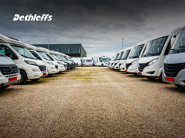 Logotipo de Dethleffs frente a las autocaravanas que esperan a ser cargadas.