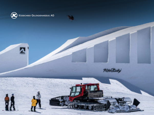 Un PistenBully de Kässbohrer y unos esquiadores de snowboard con las montañas de The Nines al fondo