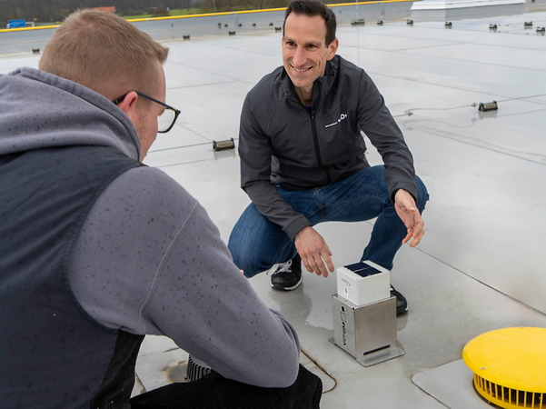 Sita’s CEO demonstrates a flat-roof monitoring device to customers.