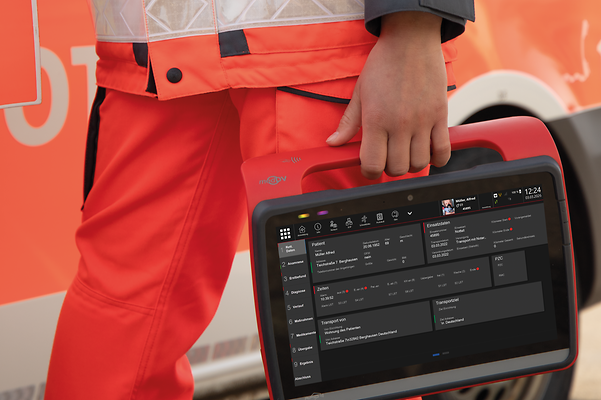 Rettungskraft hält ein Tablet mit digitaler Einsatzdokumentation vor einem Rettungswagen.