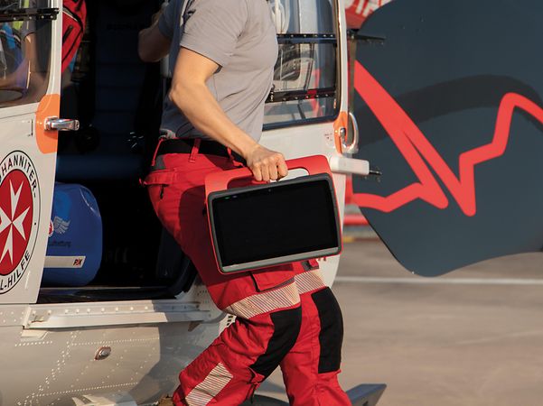 Rettungskraft trägt ein robustes Tablet beim Aussteigen aus einem Rettungshubschrauber.