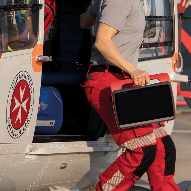 Rettungskraft trägt ein robustes Tablet beim Aussteigen aus einem Rettungshubschrauber.