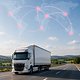 A lorry on a motorway, featuring a digital world map and connected locations for global IoT connectivity.