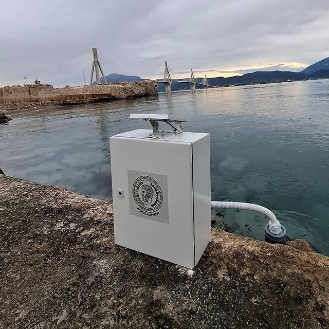A monitoring station on the riverbank for monitoring water quality, with a bridge in the background.
