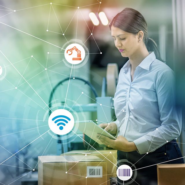 Eine Frau schaut auf ein Tablet in einem Lager mit Paketen