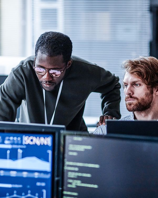 Zwei Personen im Büro analysieren IoT-Daten am Computer 