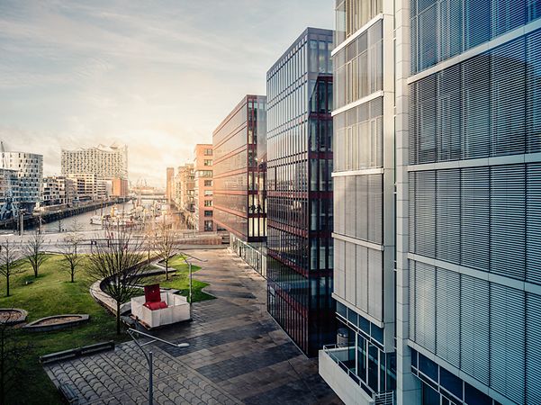 Moderne Gebäude mit Glasfassaden und Grünflächen symbolisieren die Zukunft der smarten Gebäudeverwaltung