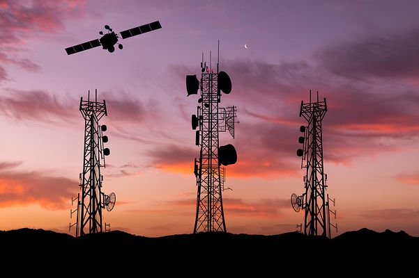 Sendemasten und Satellit vor Sonnenuntergang symbolisieren lückenlosen Empfang weltweit.