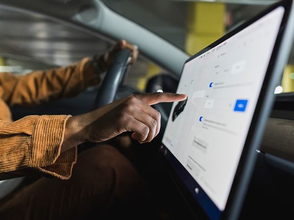 Eine Hand bedient einen Auto-Touchscreen, der mit HotSpot Drive während der Fahrt online ist.